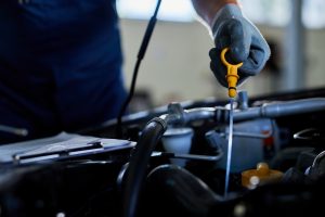 Imagem que mostra um mecânico puxando uma paleta de óleo do motor do carro.